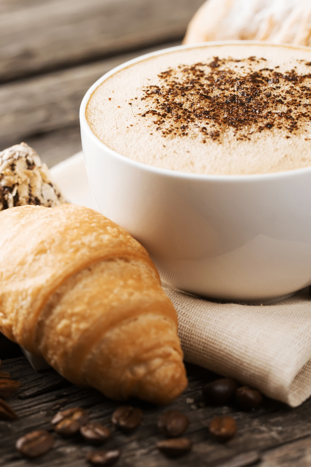 Чашка капучино на столе круассанами