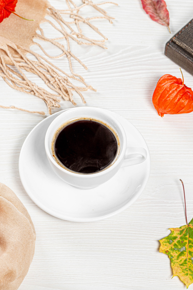 Чашка кофе на столе с книгой, очками и физалисом