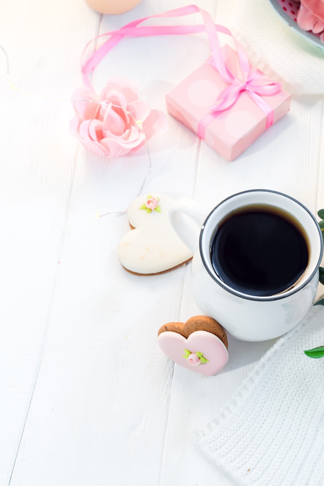 Чашка кофе на столе с печеньем в форме сердца и подарком