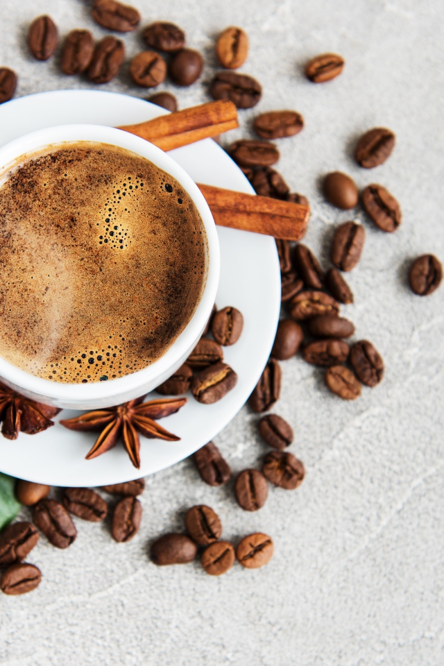 Чашка кофе с кофейными зернами на столе с корицей и бадьяном
