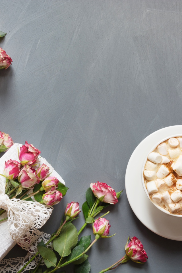 Чашка кофе с маршмеллоу на столе с подарком и букетом роз