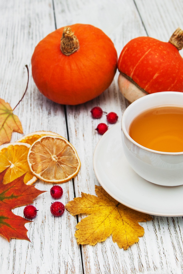 Чашка чая на столе с опавшими листьями и тыквой