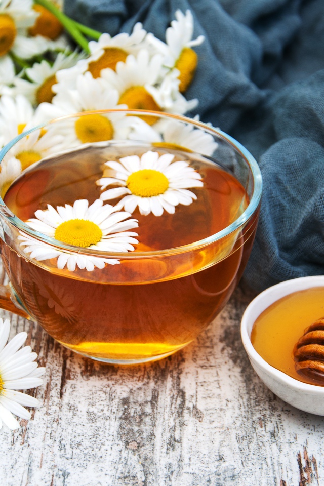 Чашка чая на столе с медом и букетом ромашек