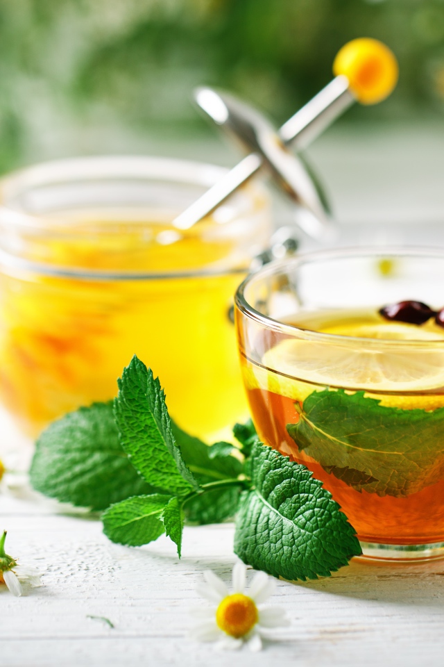 Чашка чая с лимоном и мятой на столе с медом