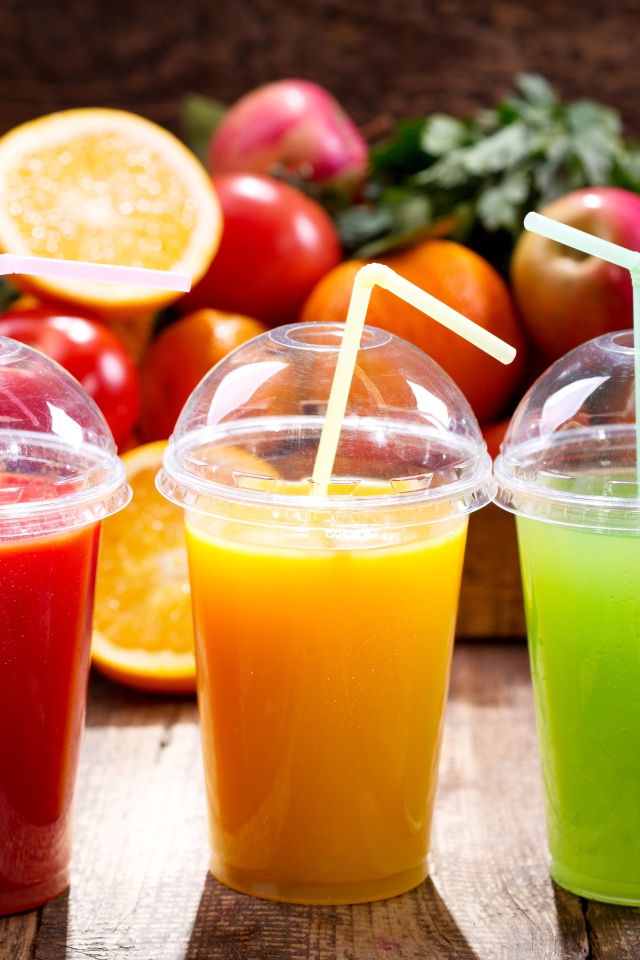 Свежие соки в стаканах с трубочками на столе