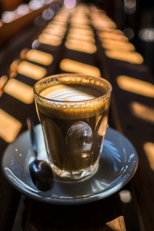 Стакан с кофе стоит на деревянном лавке