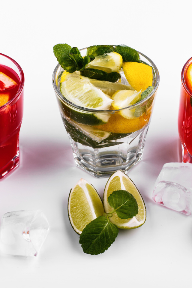 Стаканы с цитрусовыми коктейлями со льдом на белом фоне с фруктами