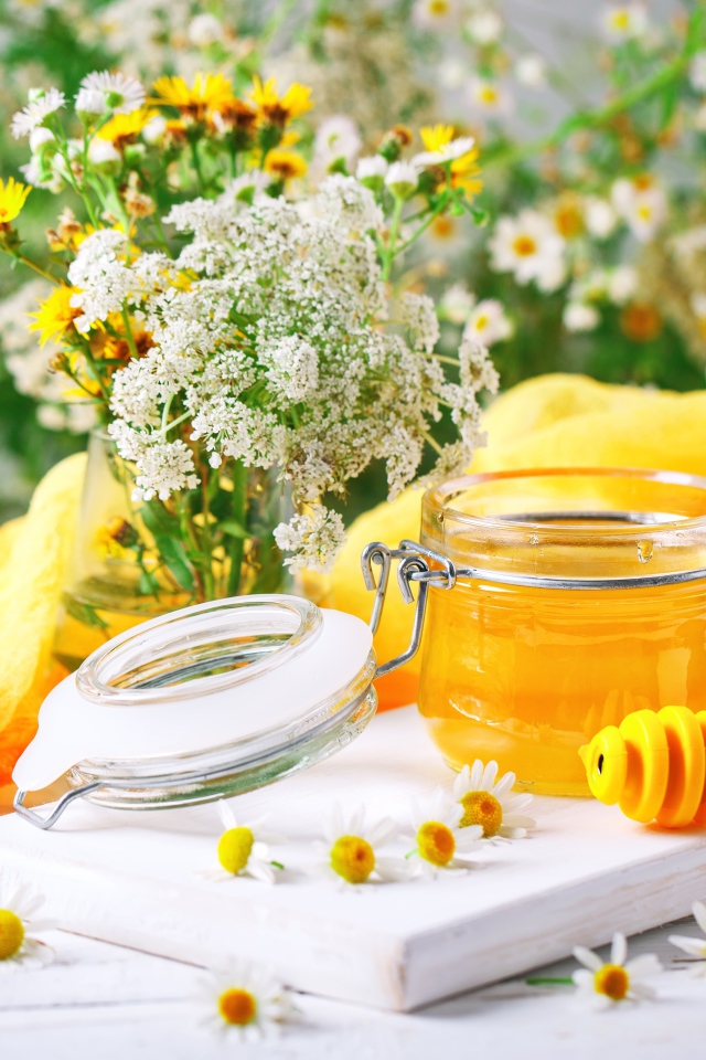 Банка меда на столе с цветами