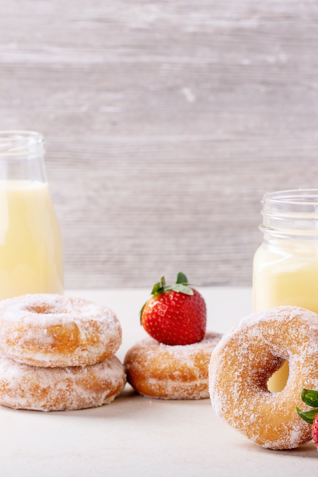 Молочные коктейли на столе с клубникой и пончиками