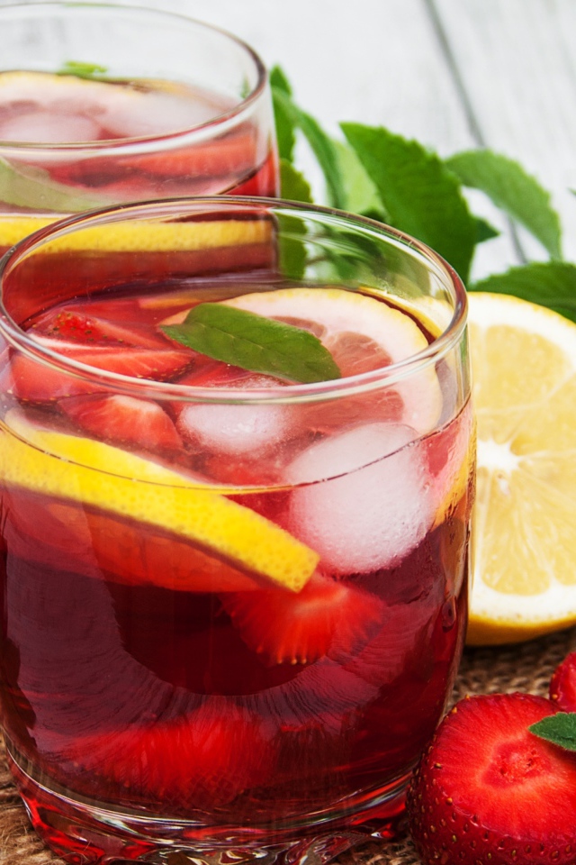 Мохито в стаканах на столе с клубникой, лимоном и мятой