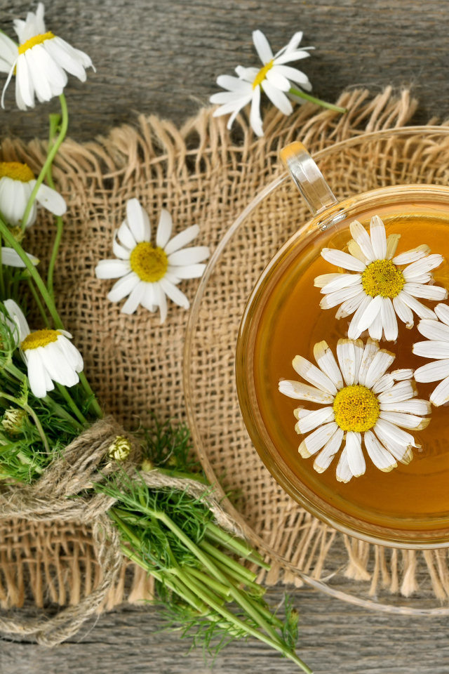 Чай в стеклянной чашке на столе с ромашкой