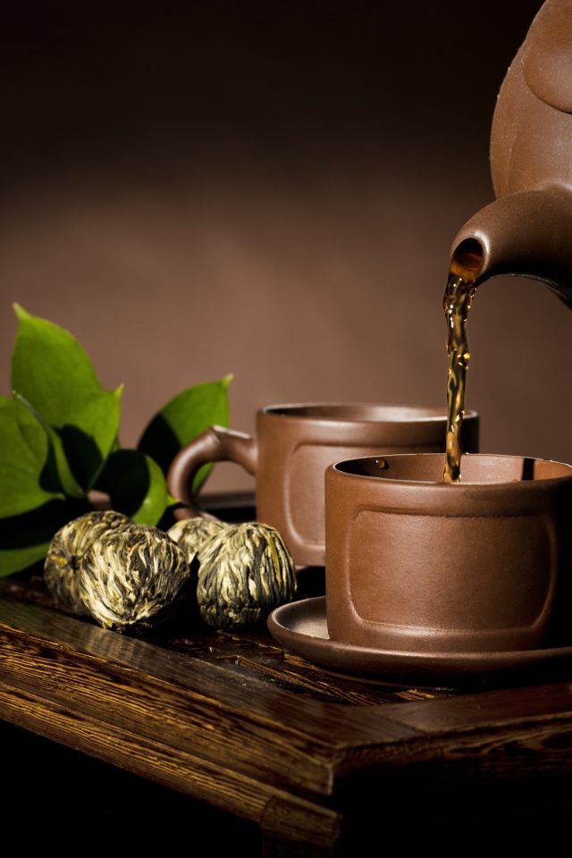 Чай наливают из чайника в коричневую чашку