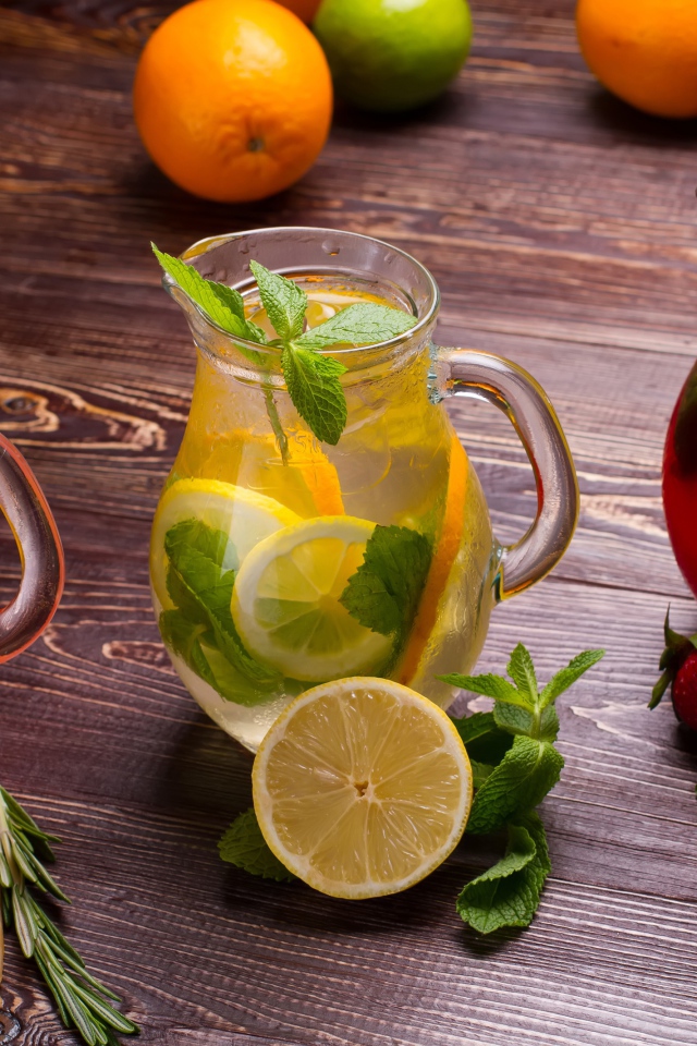 Три стеклянных графина с напитком на деревянном столе с фруктами