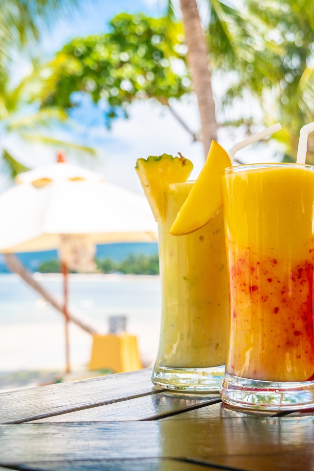 Два цитрусовых коктейля на столе на тропическом пляже