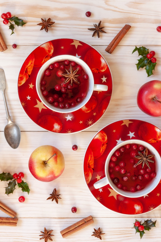 Две чашки клюквенного чая на столе с корицей, яблоками и бадьяном