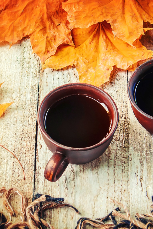 Две чашки горячего кофе на столе с сухими листьями