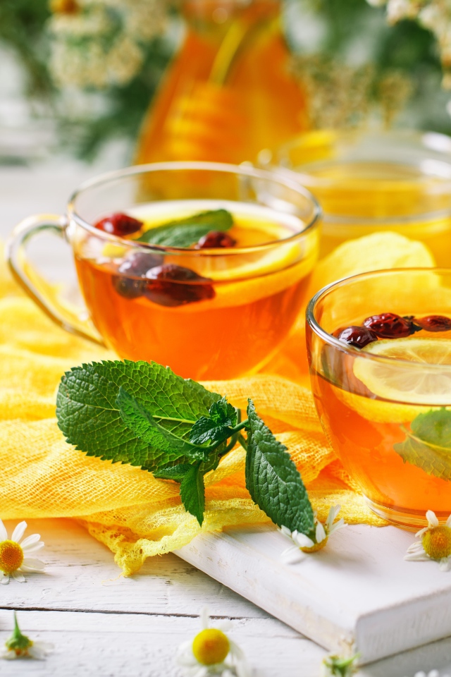 Две стеклянные чашки чая с лимоном, мятой и шиповником