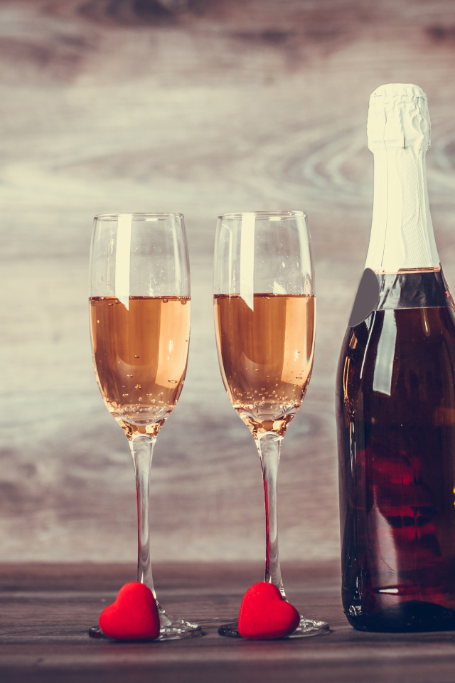 Два бокала и бутылка шампанского на столе с букетом роз