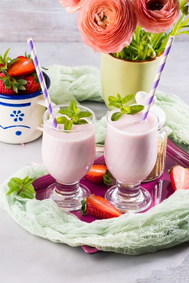 Два стакана с коктейлем на столе с букетом и клубникой