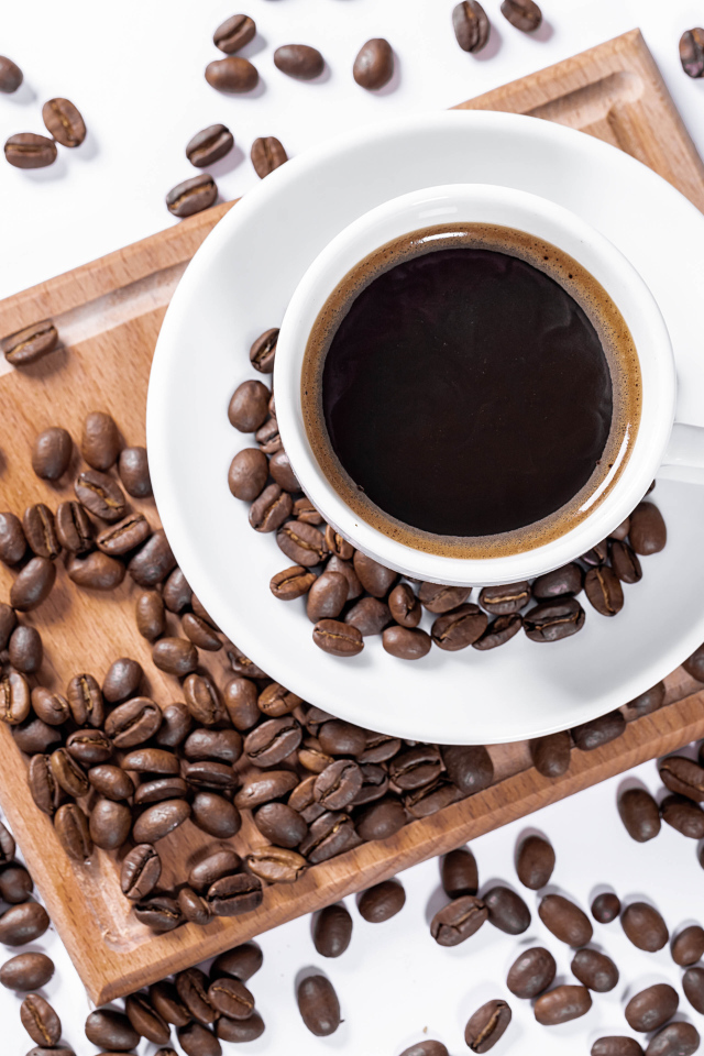 Белая чашка кофе на доске с кофейными зернами