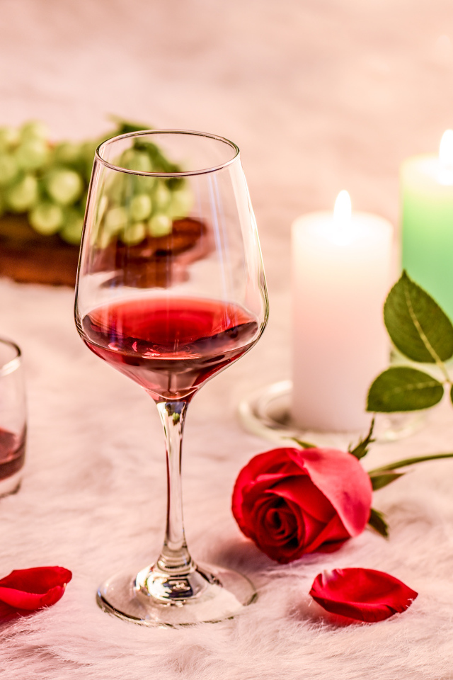 Вино на кровати с розой, виноградом и зажженными свечами