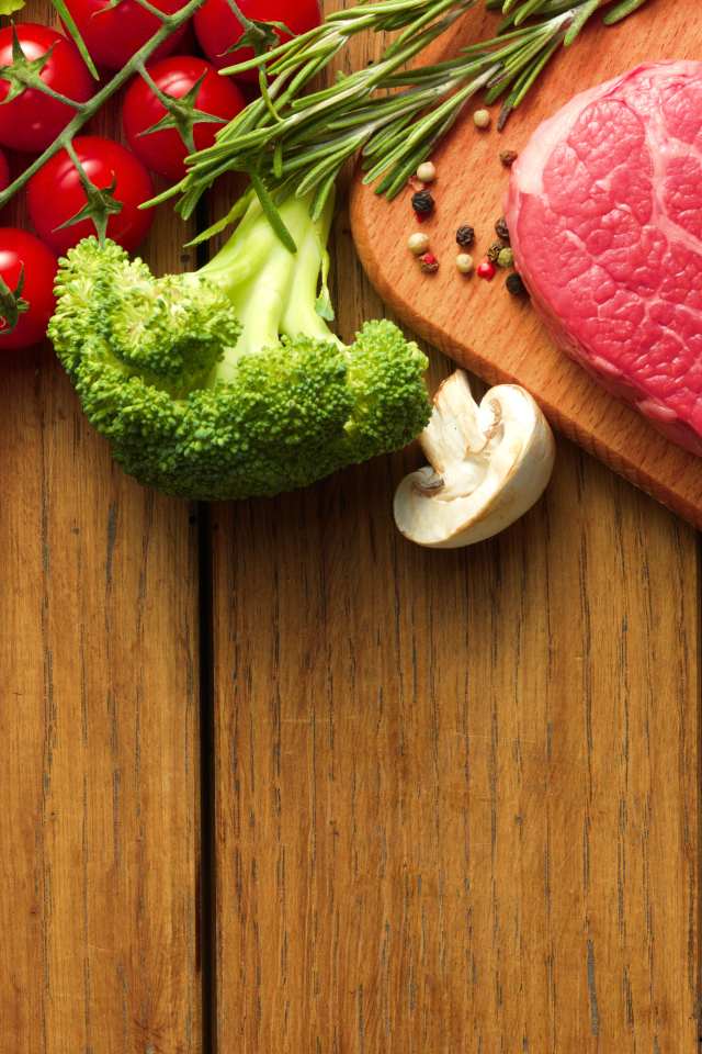 Кусок свежего мяса на столе с овощами и зеленью 