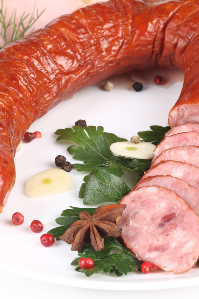 Аппетитная колбаса на белом фоне со специями и зеленью