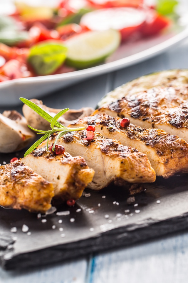Запеченное куриное мясо на доске с помидорами 