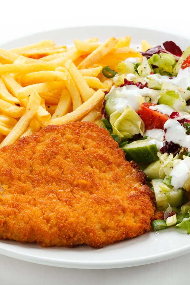 Отбивная с картофелем фри и салатом на большой белой тарелке