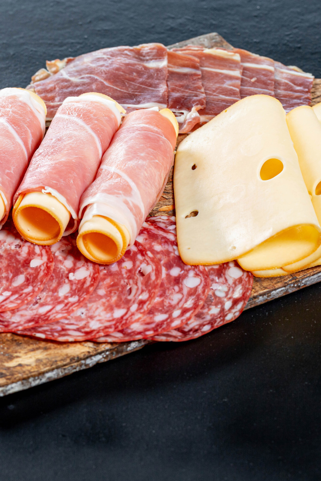 Ветчина на доске с колбасой и твердым сыром