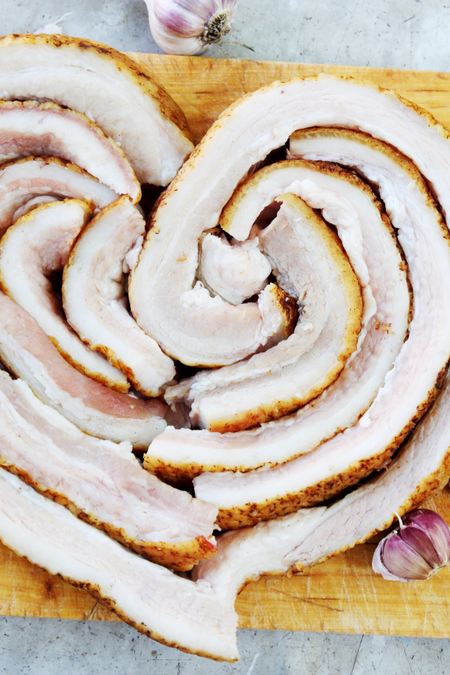 Сердце из свежего сала на доске с чесноком