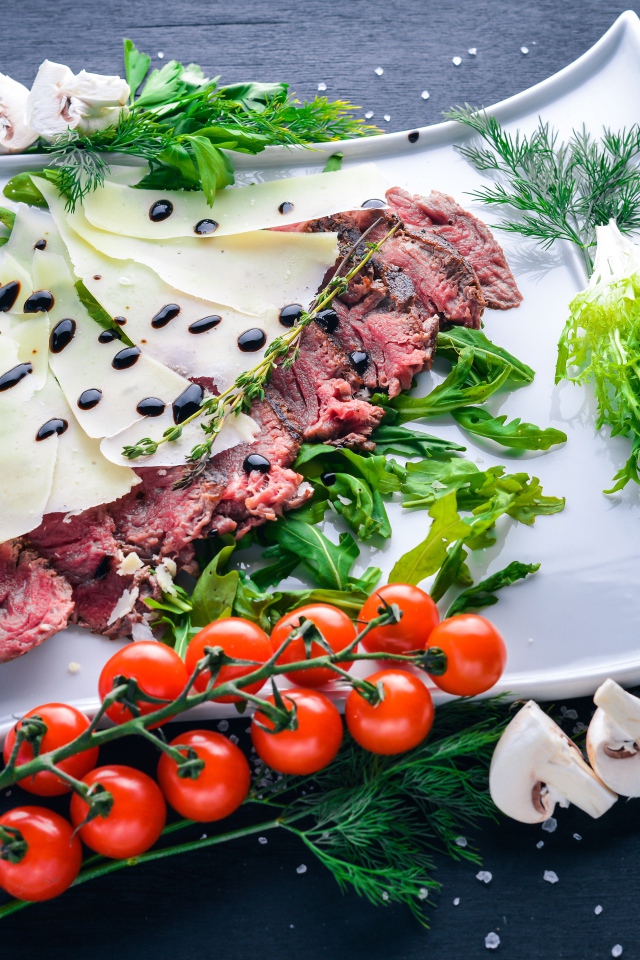 Мясо с сыром, овощами и зеленью на тарелке