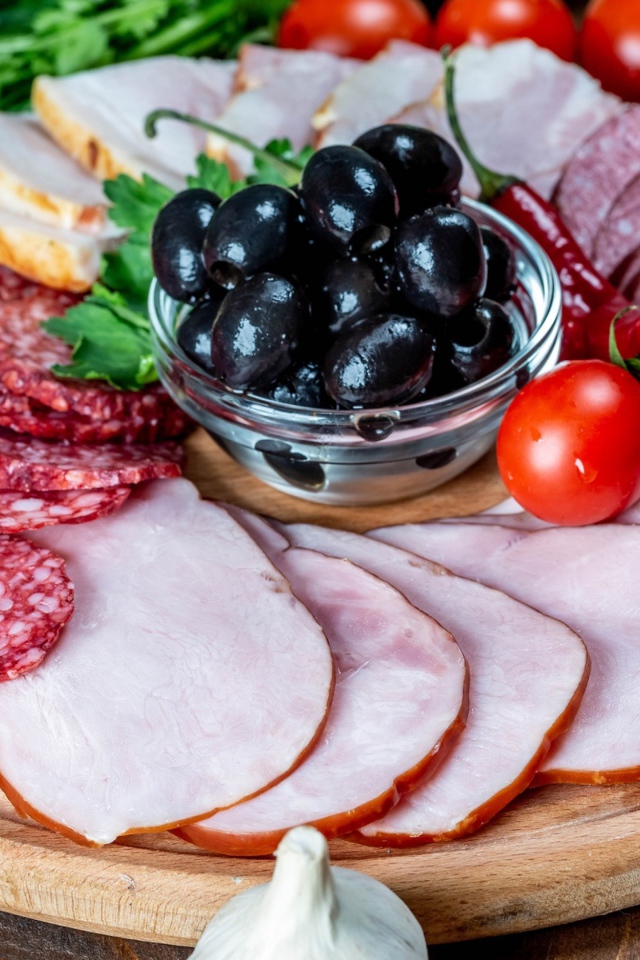 Колбасные продукты на доске с оливками