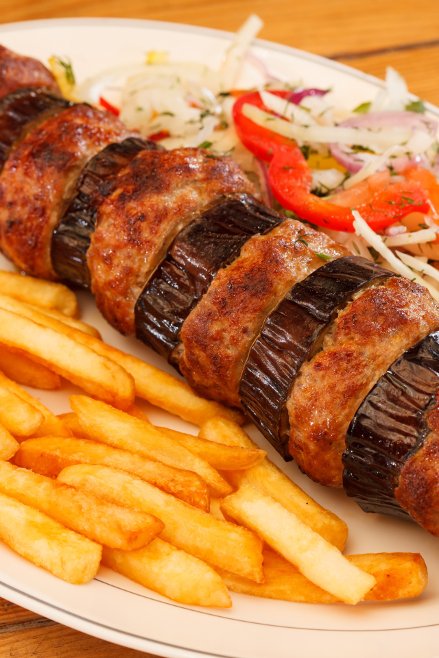 Шашлык с мясом и баклажанами на тарелке с картофелем фри 