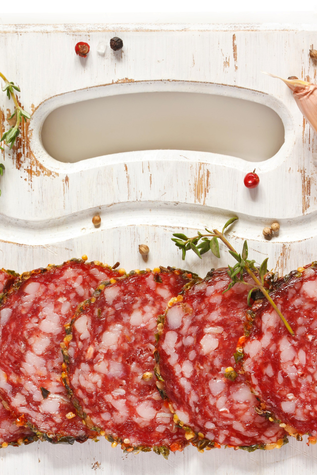 Нарезанная колбаса на разделочной доске со специями и чесноком