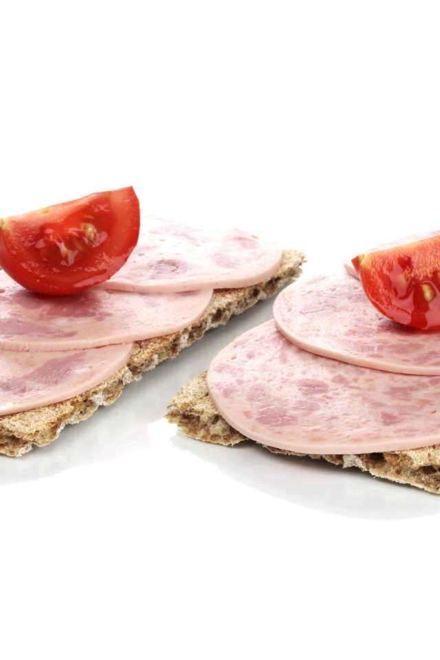 Тосты с колбасой и кусочками помидора на белом фоне