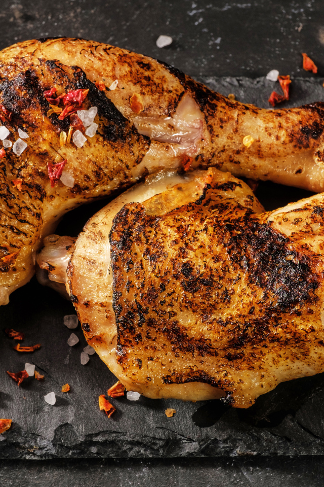 Два запеченных куриных окорочка на черном фоне