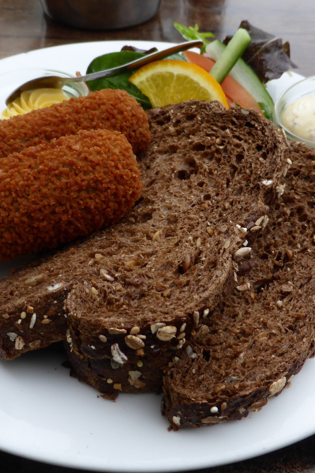 Два куска черного хлеба на тарелке с котлетами