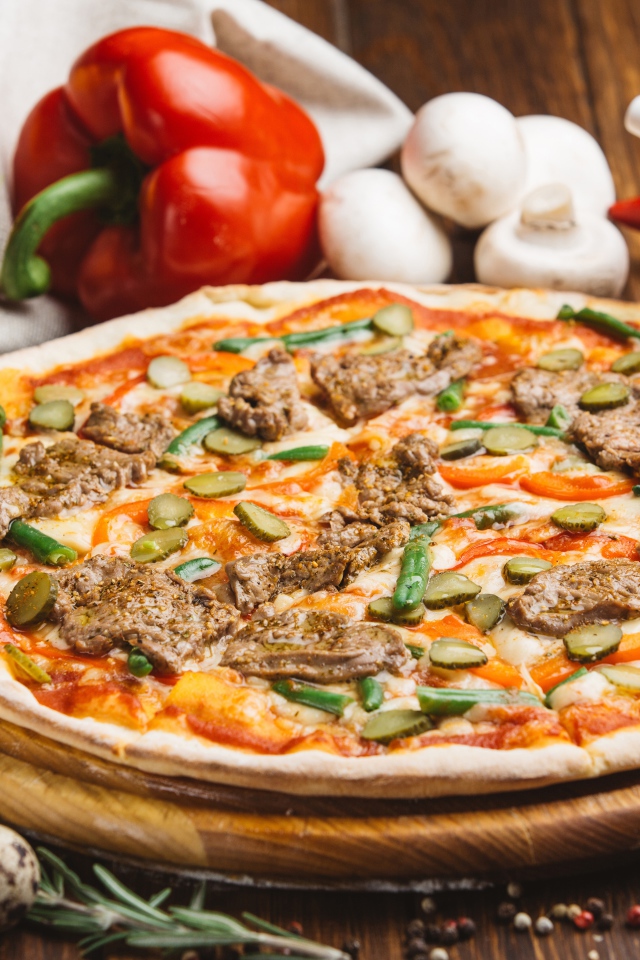 Свежая пицца с мясом и огурцами на столе с овощами