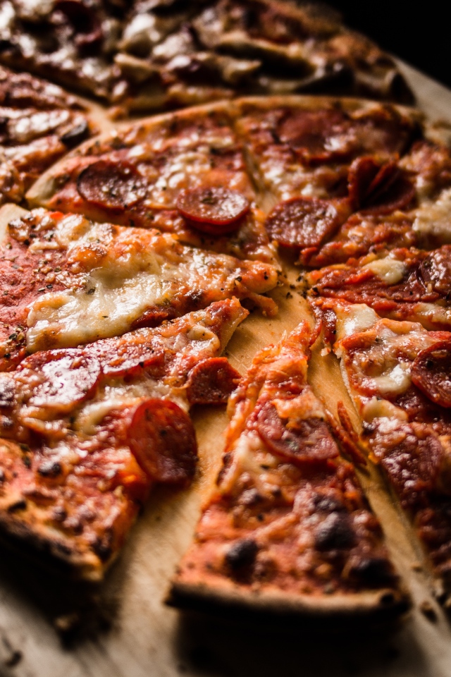 Пицца нарезана кусками на деревянной доске