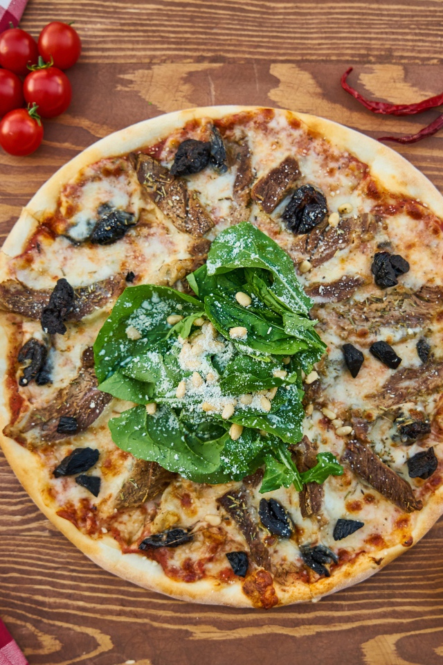 Пицца с мясом и шпинатом на столе 