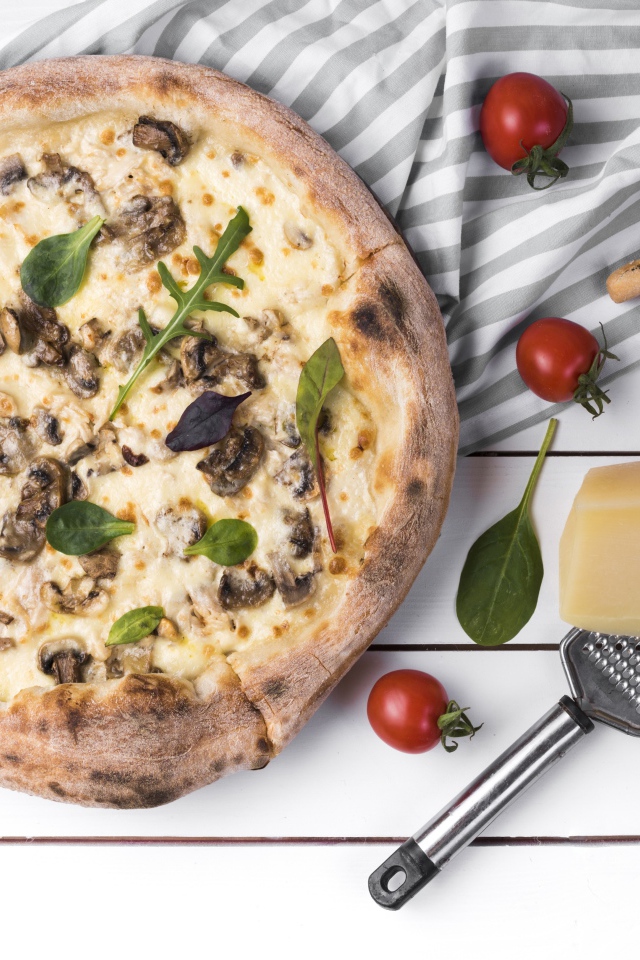 Пицца с грибами на столе с сыром и овощами