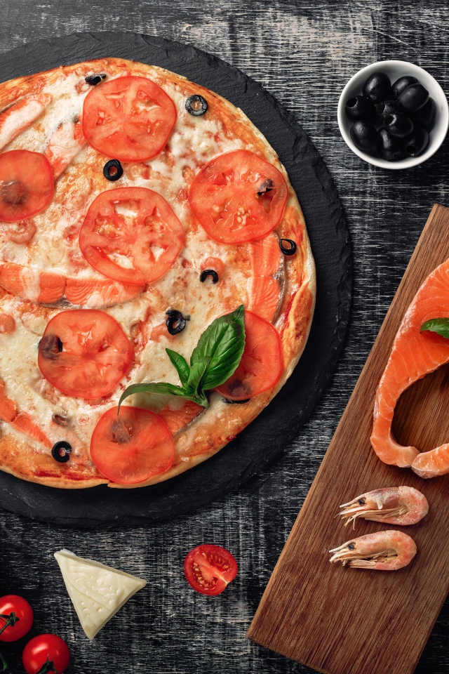 Пицца с помидорами, красной рыбой и сыром на столе 