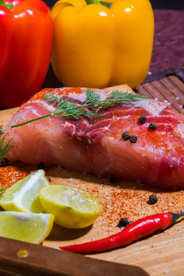 Кусок сырой рыбы на разделочной доске со специями, лимоном и болгарским перцем