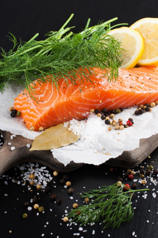 Кусок красной рыбы на доске с укропом и лимоном 