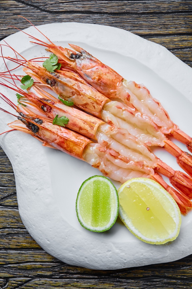 Аппетитные креветки на белой тарелке с лимоном