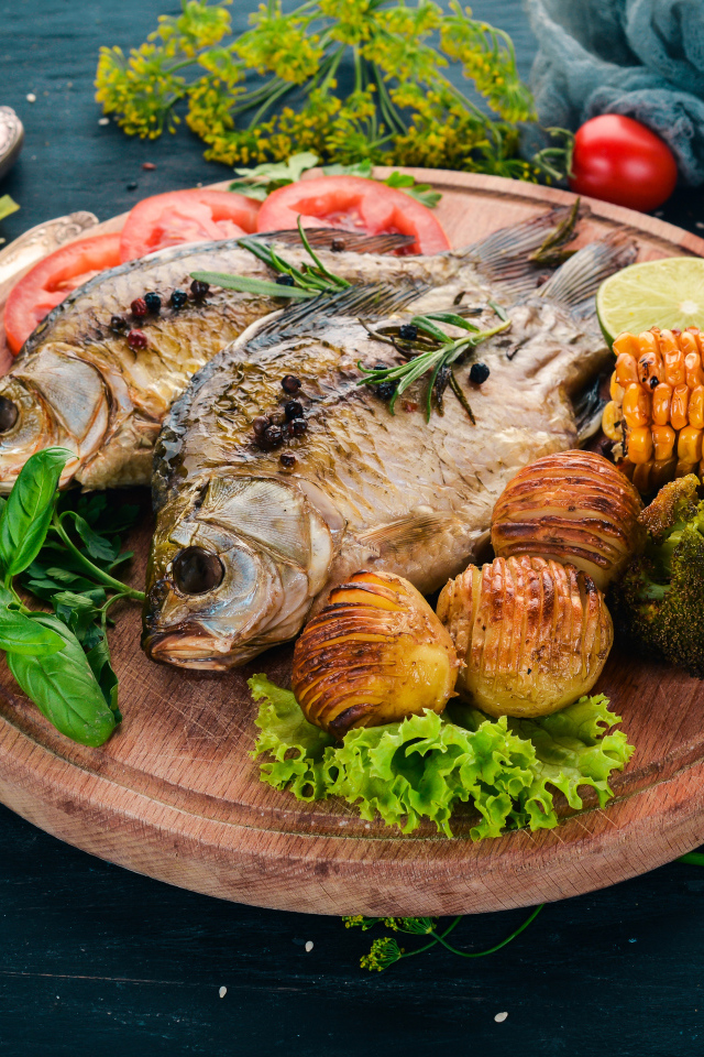 Запеченная рыба на разделочной доске с овощами 