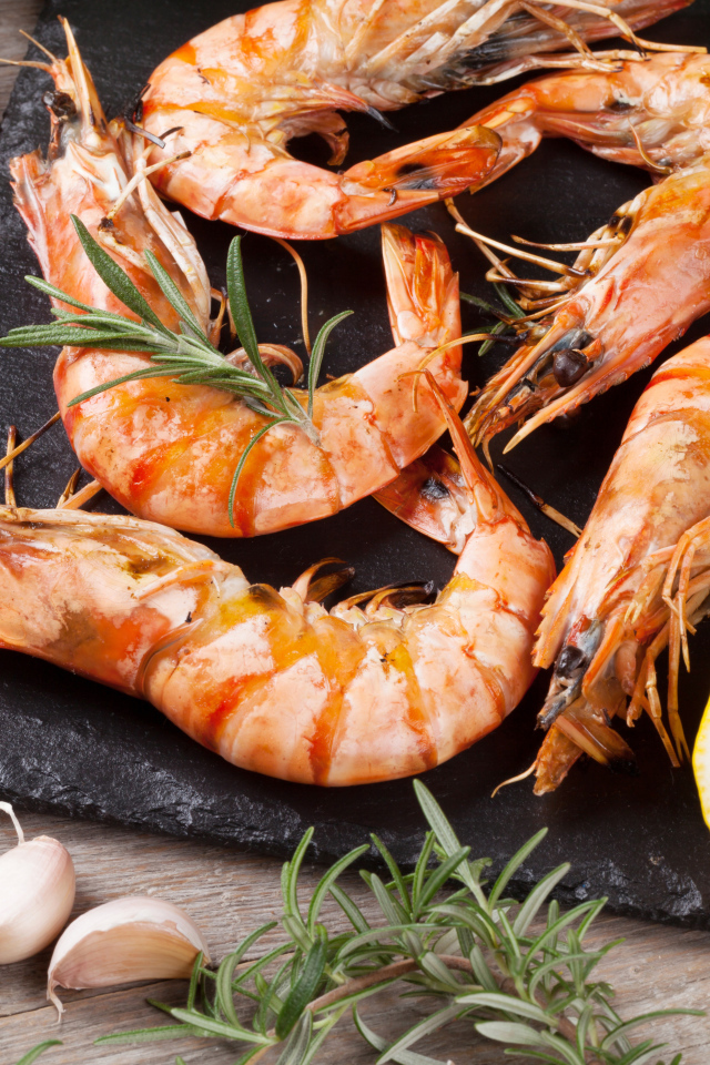 Вареные креветки на столе с лимонами и помидорами