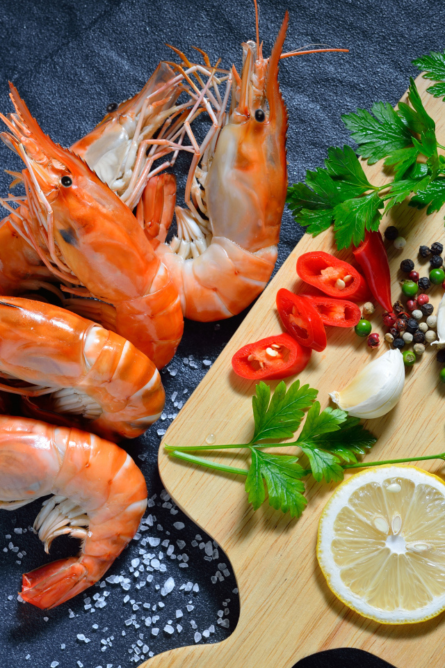 Вареные креветки на столе со специями и зеленью