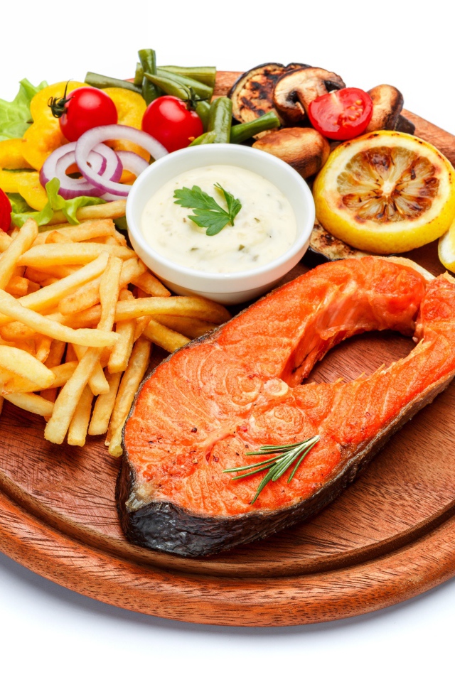 Рыба на доске с картофелем фри, овощами и соусом